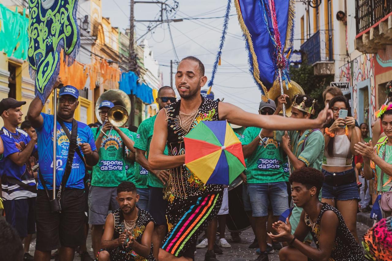 Passista dançando frevo com sombrinha colorida nas ruas de Olinda